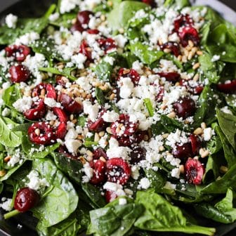 cherry salad with toasted pine nuts and goat cheese on a platter.