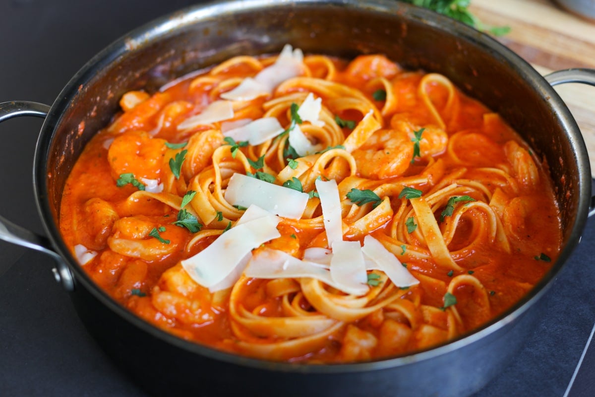 shrimp pasta in pan with cheese and parsley.