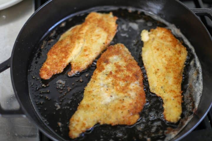 shallow frying crispy chicken cutlets in a pan.