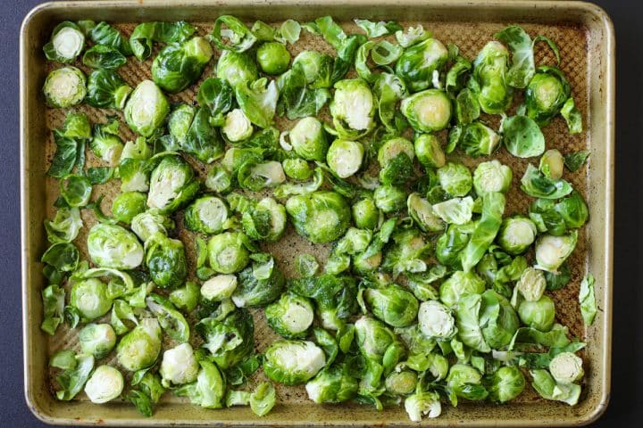 Brussels sprouts on the tray - seasoned with kosher salt and cracked black pepper.