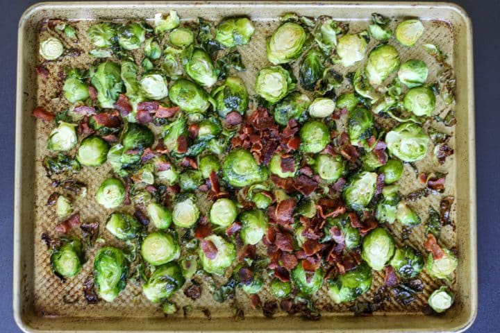 Cooked Brussels sprouts on the tray with cooked and crumbled bacon.