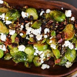 Brussels sprouts with bacon, cranberries, goat cheese and toasted pecans in a bowl.