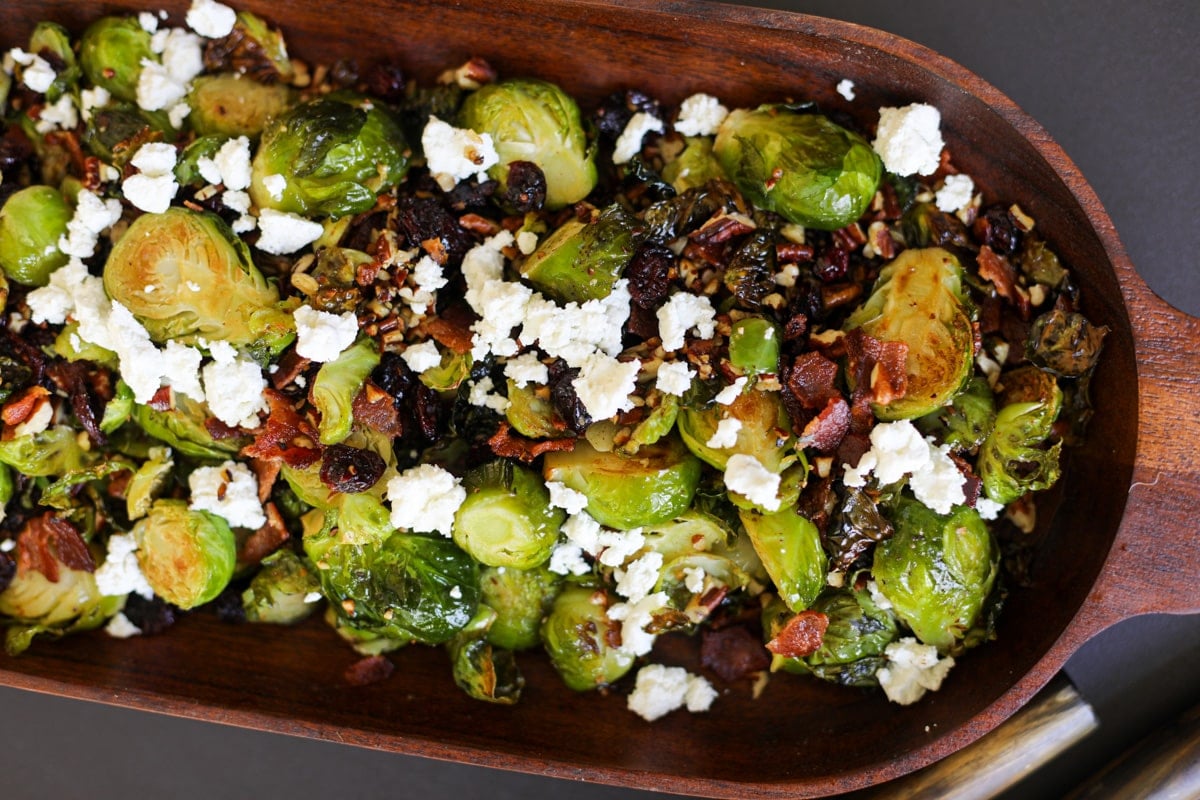 Brussels sprouts with bacon, cranberries, goat cheese and toasted pecans in a bowl.