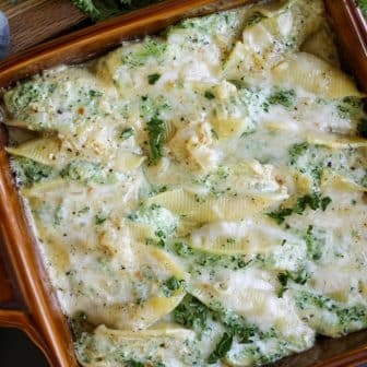 overhead image of cheesy stuffed shells with pesto sauce.