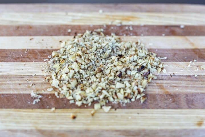 toasted walnuts chopped small on a cutting board.