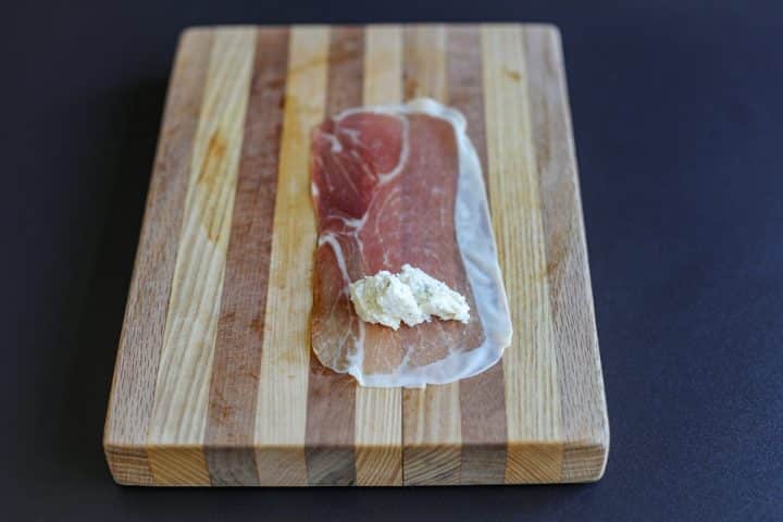 one slice of prosciutto on a cutting board with a dollop pf Boursin cheese.