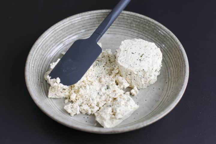 Boursin cheese being pressed into a bowl evenly.