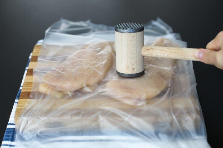 chicken breasts being pounded with a mallet.