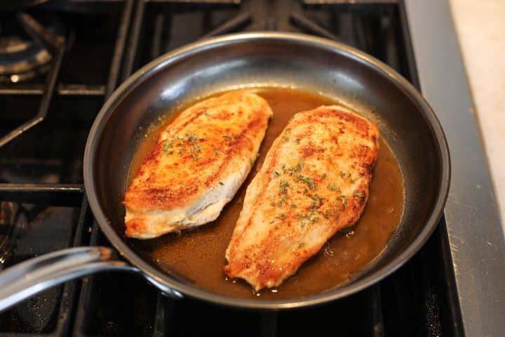 chicken breasts in a pan with fresh thyme.