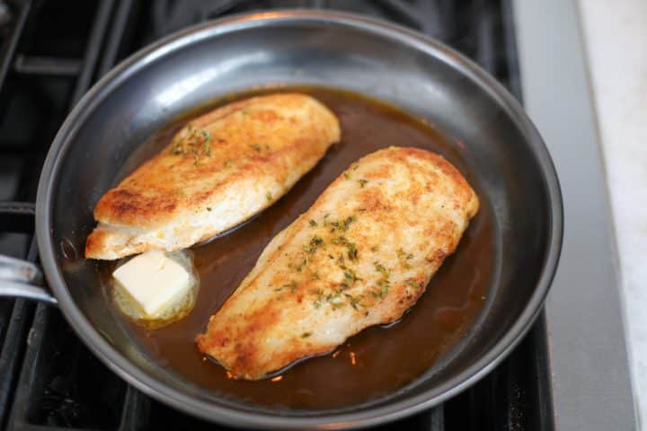 chicken breasts with pan sauce and butter in a pan.