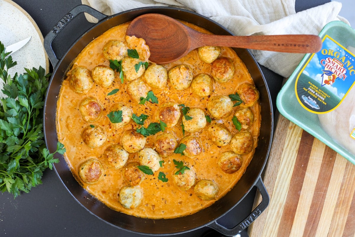 chicken meatballs in a pan with a spoon and Smart Chicken packaging.