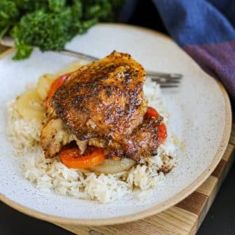 one baked chicken thigh on a plate.