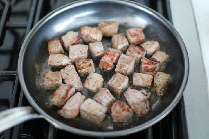 browned steak bites in a pan.