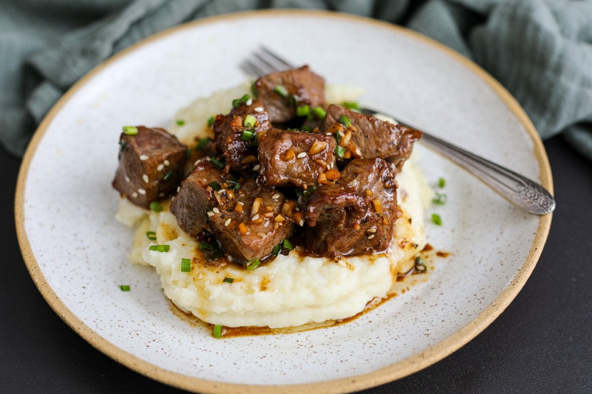 steak bites loaded on top of mashed potatoes.