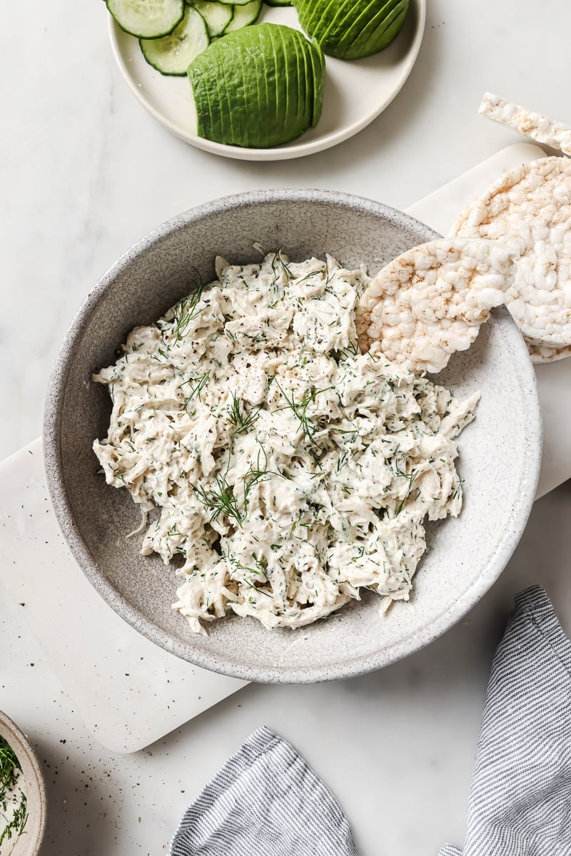 Tzatziki Chicken Salad in a bowl, alongside avocado. 