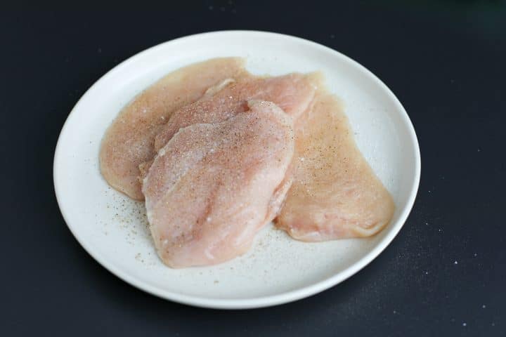 seasoned chicken cutlets on a plate. 