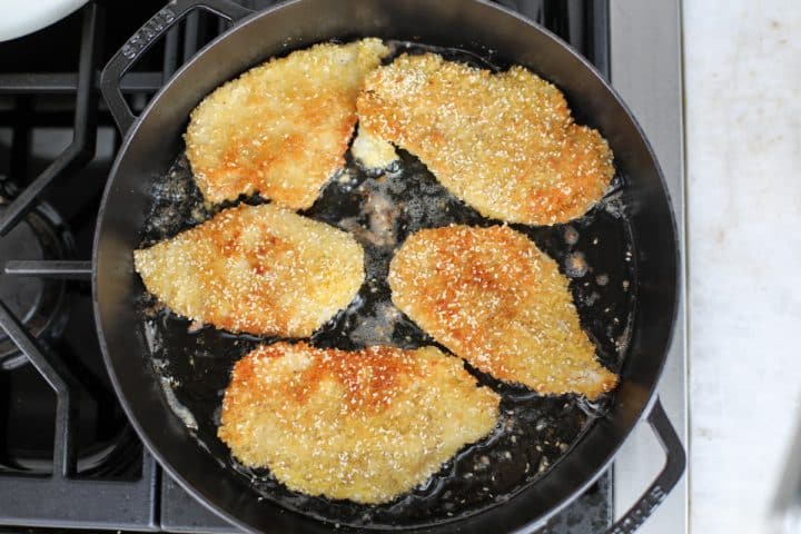 golden brown chicken cutlets in a pan. 
