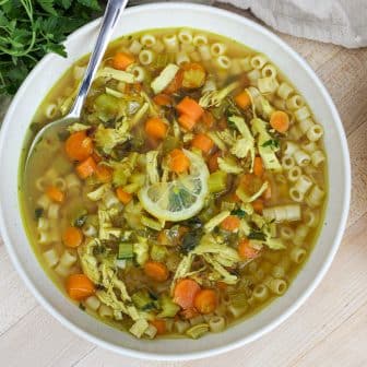 Lemon Chicken Soup in a bowl next to crusty bread.