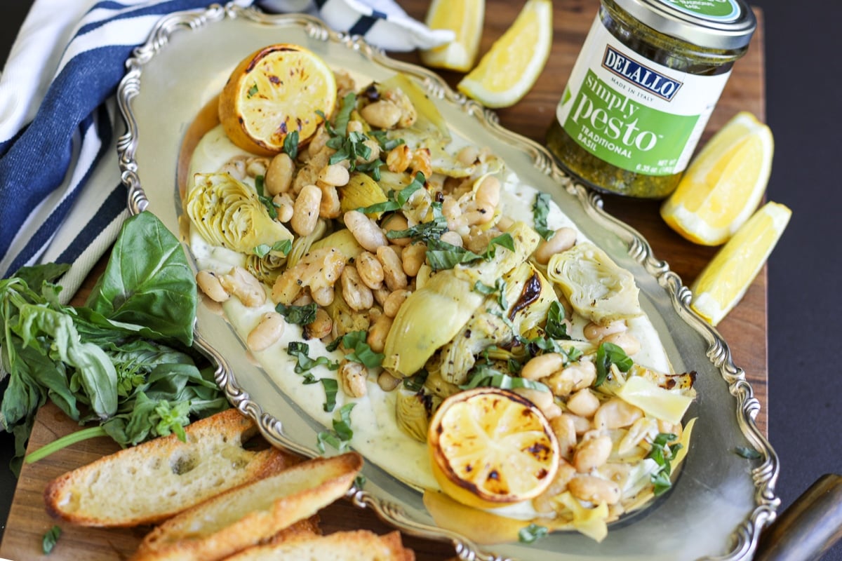 roasted artichokes and beans with a jar of pesto.