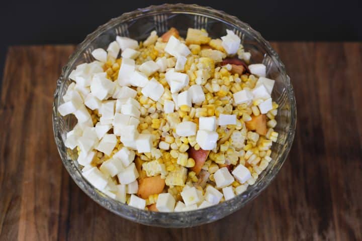 cheese in a bowl with peaches, corn and chicken.
