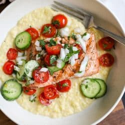 Grilled salmon over creamed corn and tomato salad in a bowl.