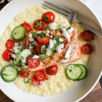 Grilled salmon over creamed corn and tomato salad in a bowl.
