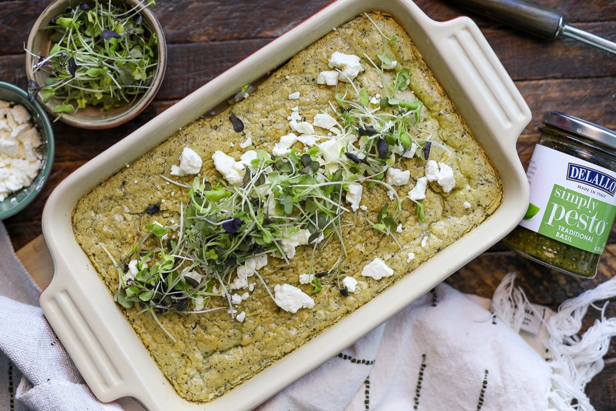 pesto baked eggs with delallo jar next to the baking dish.