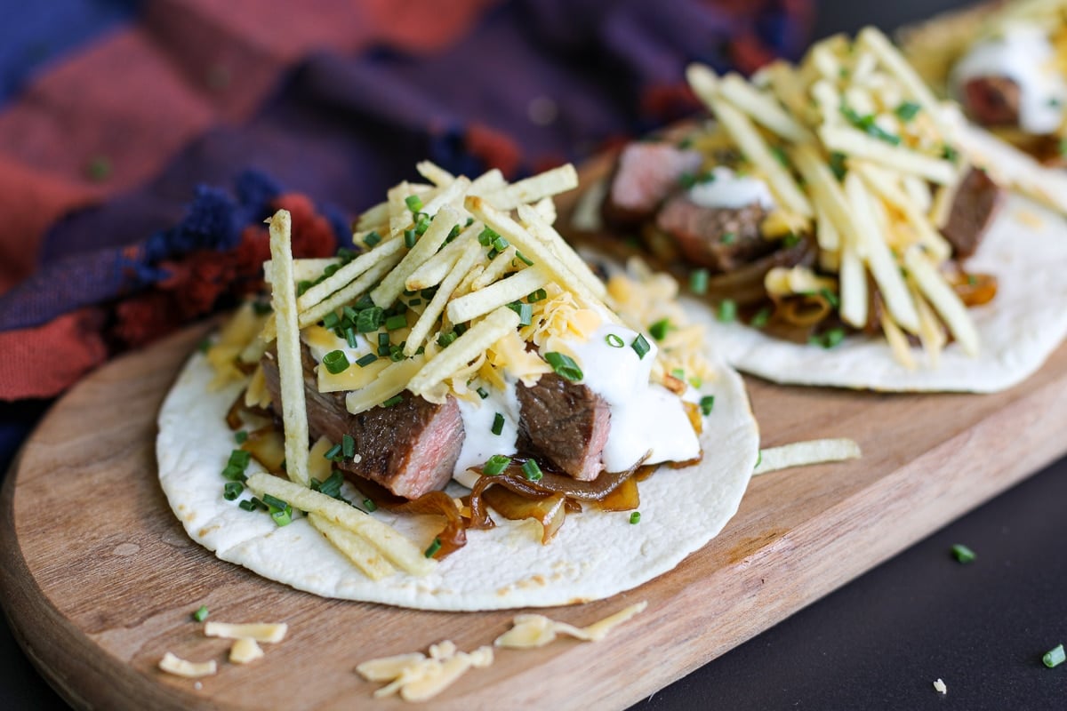 steak taco with caramelized onions, cheddar cheese and potato sticks.